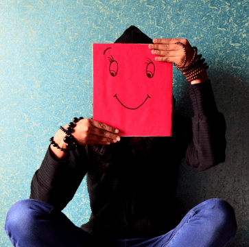 A man covering his face with a smiley picture